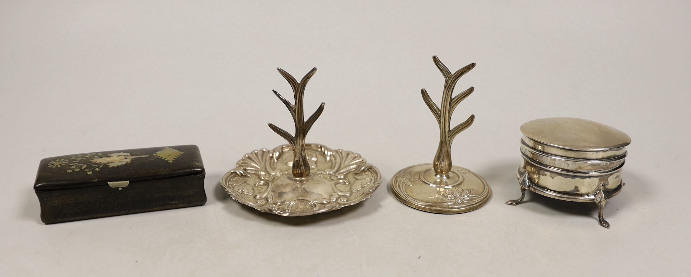 Two early 20th century silver ring stands, tallest 7cm, a small silver mounted trinket box and a 19th century inlaid wooden snuff box